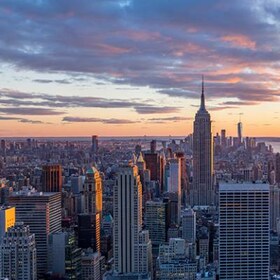 A panoramic view of the iconic New York City skyline at dusk, featuring the Empire State Building and other prominent skyscrapers, symbolizing the vast commercial properties that benefit from Siplast roofing and waterproofing guarantees and reliable systems.