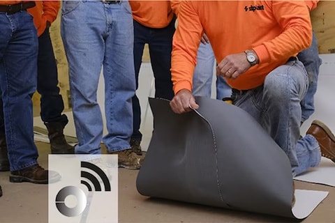 A Siplast RoofTag being embedded into an SBS-modified bitumen membrane by a roofer, demonstrating the technology for roof asset identification and Certificate of Analysis.