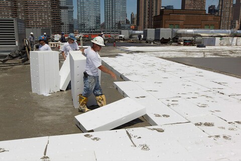 Construction workers installing lightweight insulating concrete panels on a rooftop